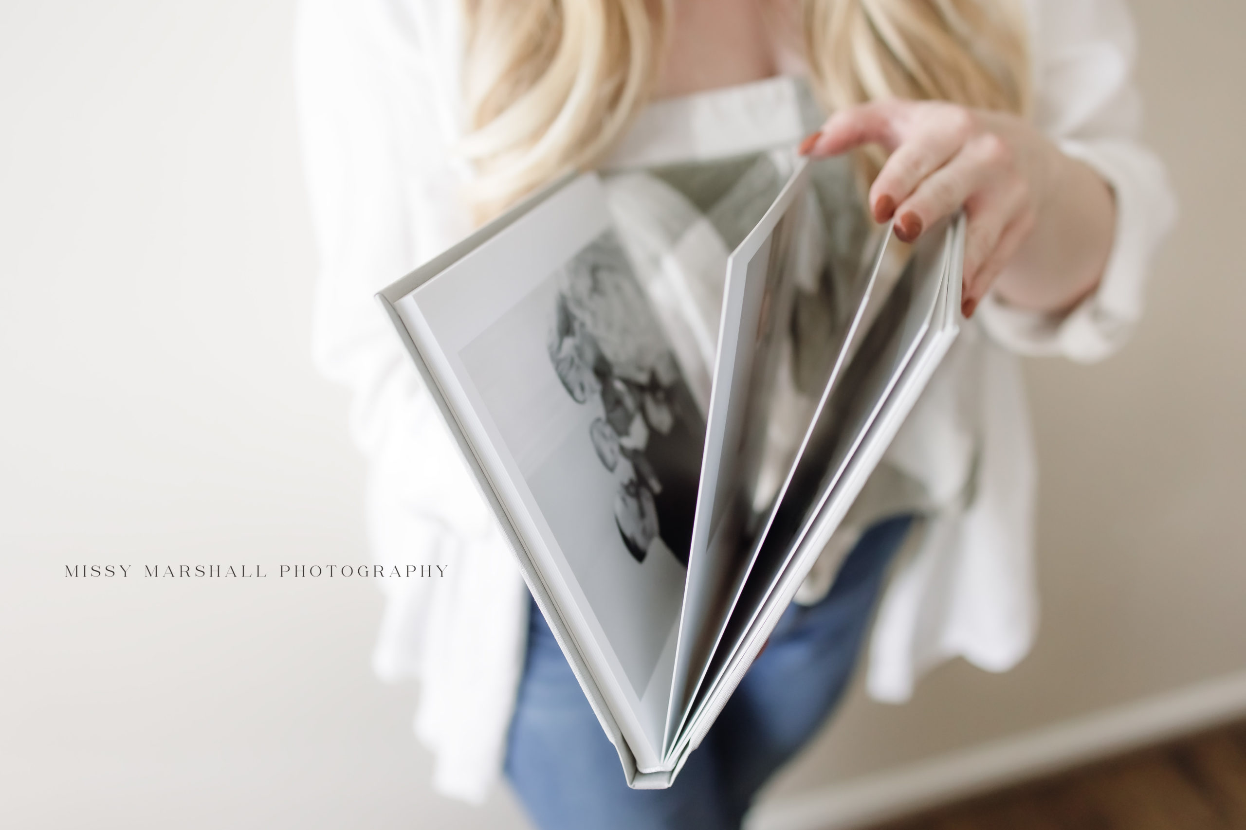 Louisville maternity photographers | Missy Marshall Photography holding a custom album in a bright studio