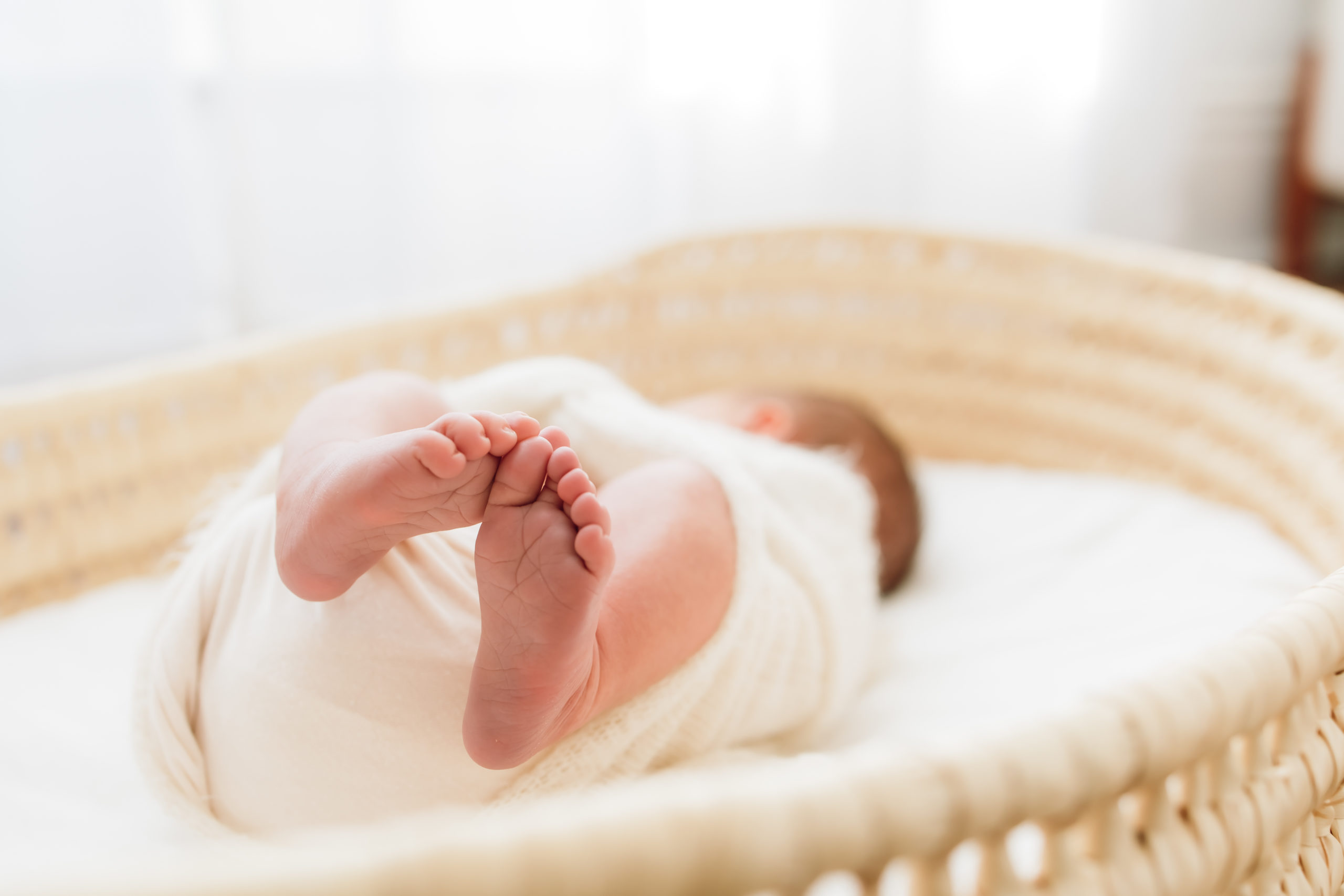 Louisville KY Newborn Photographer - newborn baby laying in a basket dressed in white in a bright, warm studio in Louisville Kentucky