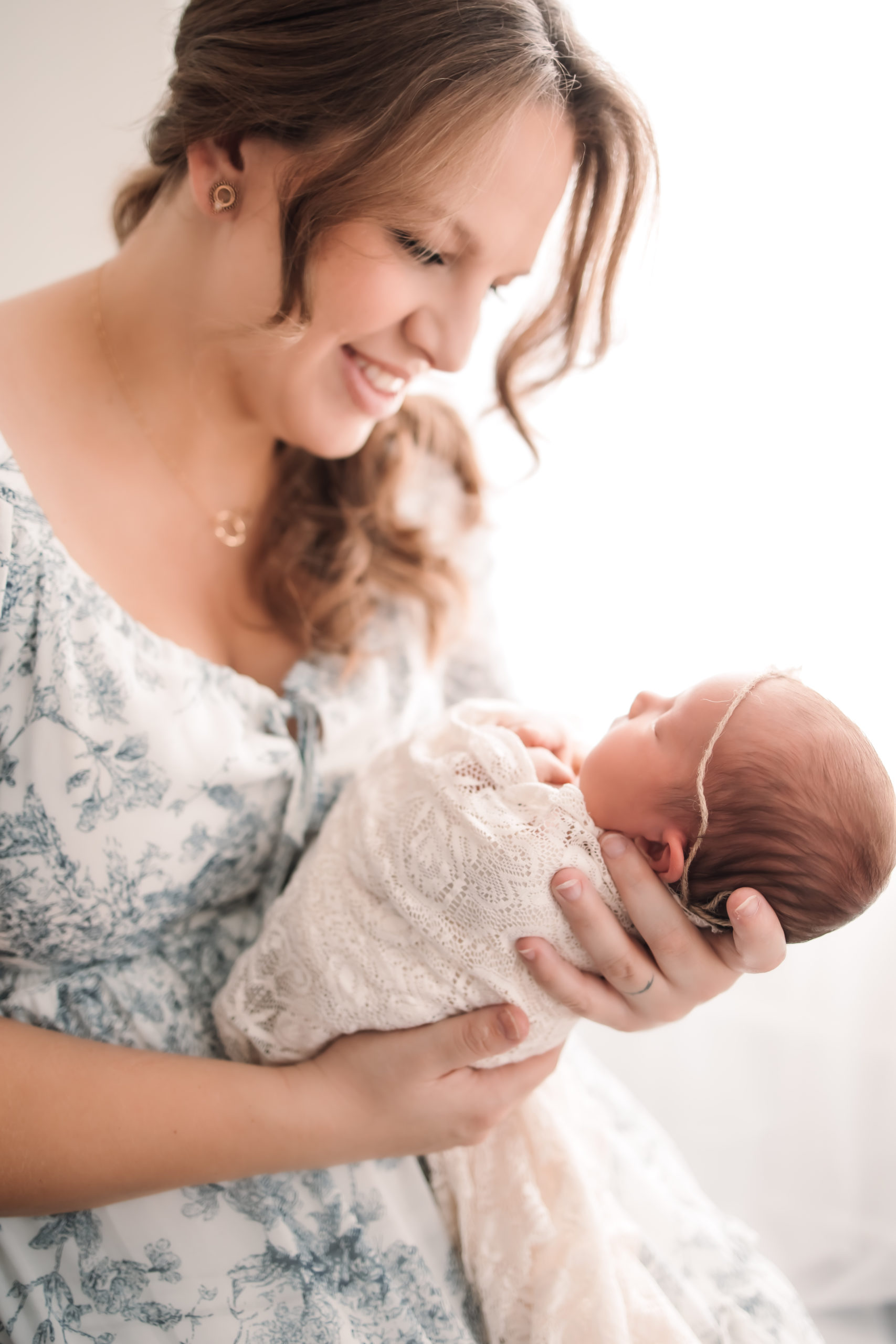 New mom smiling at her newborn baby in a bright white studio in Louisville