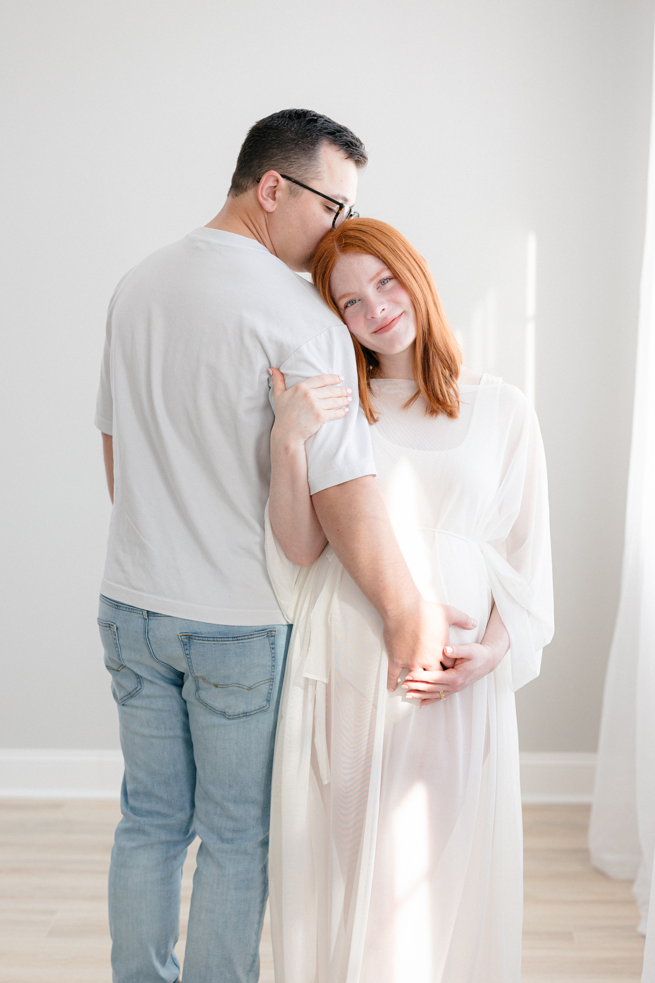 Mom and dad standing and embracing during their maternity session in a Louisville KY photography studio