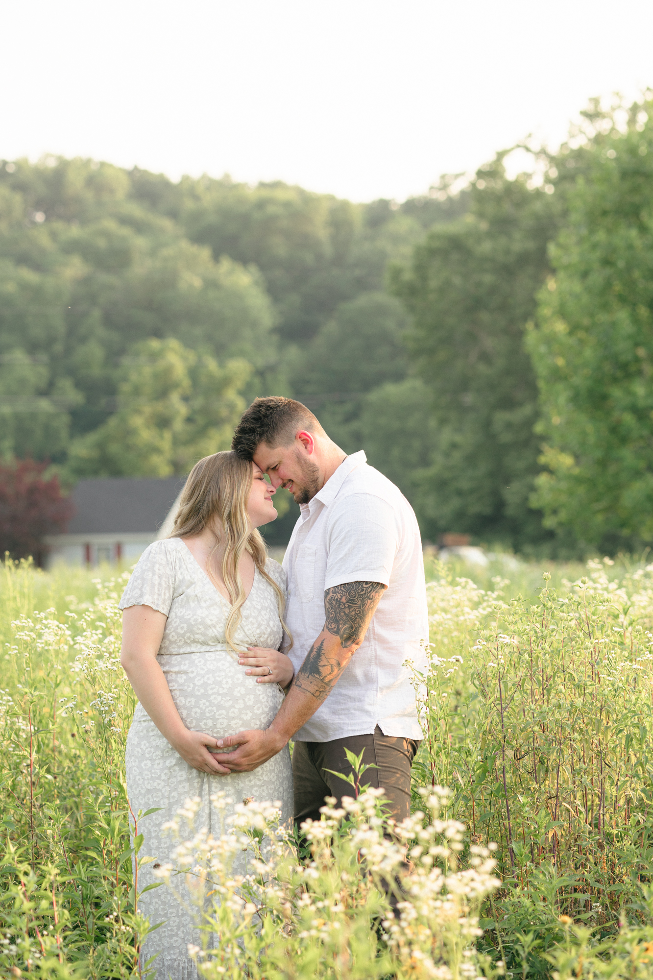 Portrait of a new mom and dad embracing in a field of wildflowers taken by one of the best Louisville maternity photographers Missy Marshall